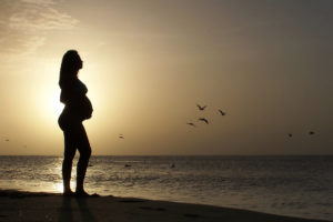 Mulher grávida olhando para o mar